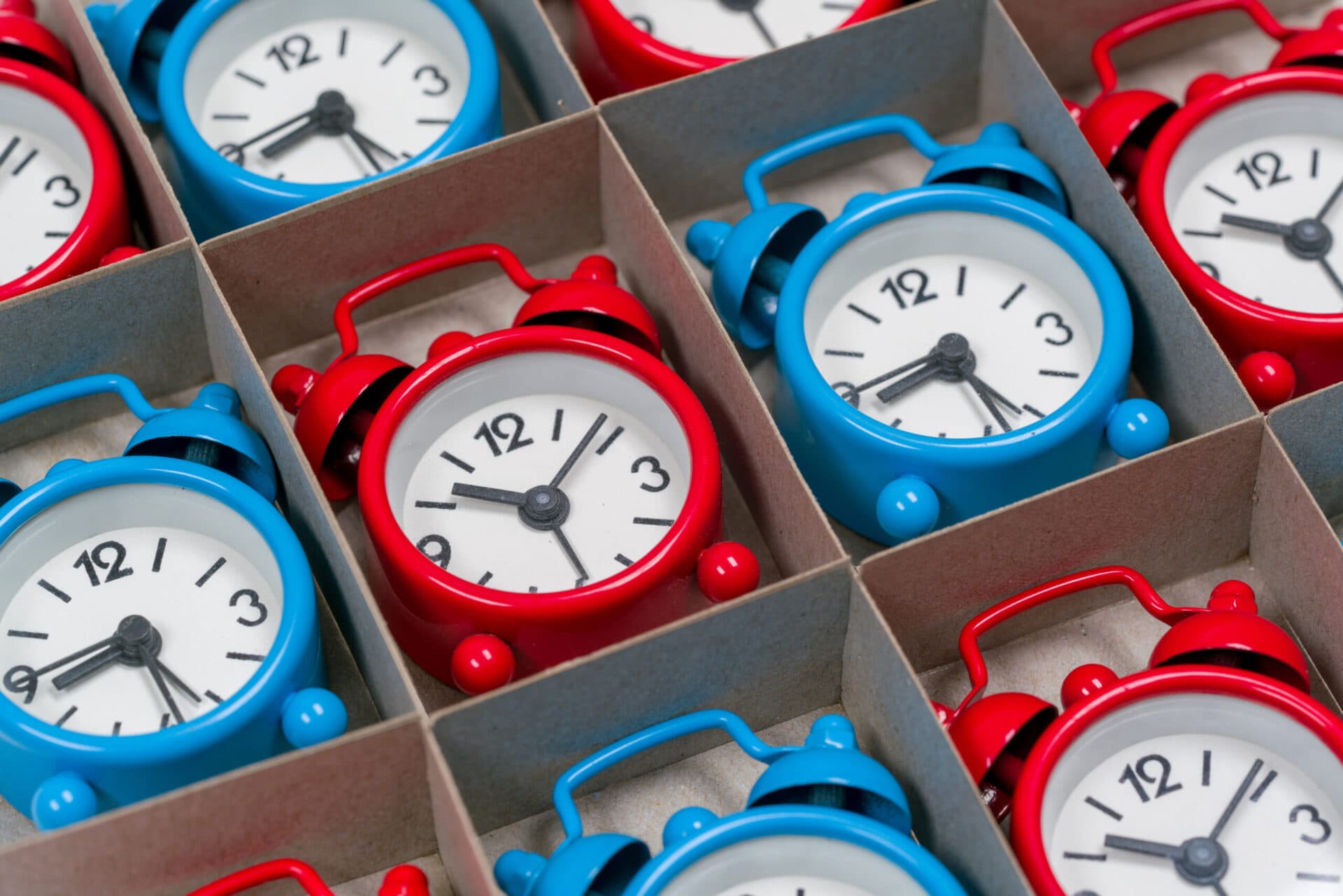 Rows of small red and blue alarm clocks in a divided box