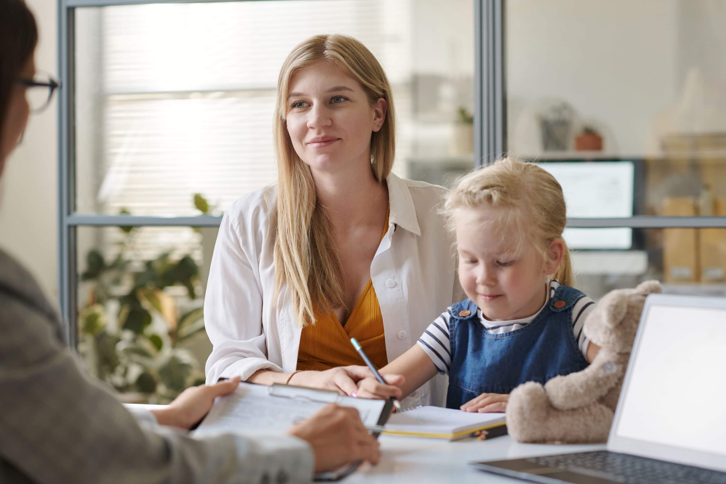A parent and child reviewing their child's progress with a teacher at Creative Playrooms